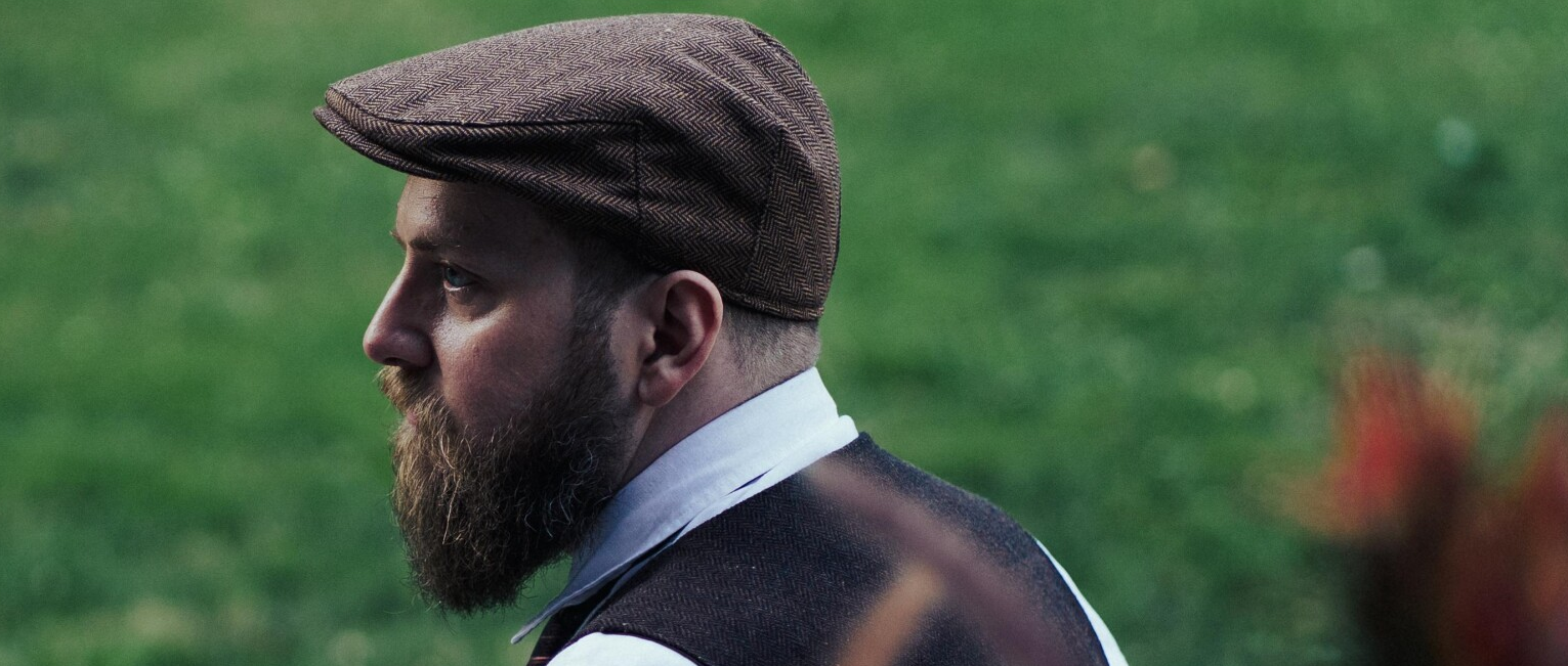 Your humble developer with a big beard wearing a herringbone vest and a newsboy cap